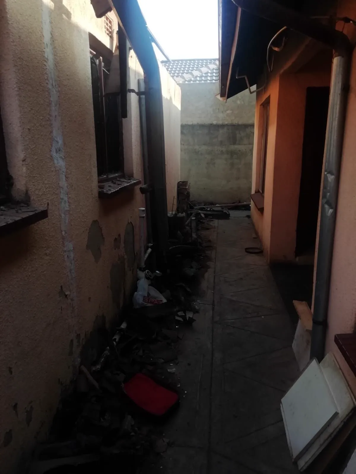 A passage beside the house, covered in fire debris