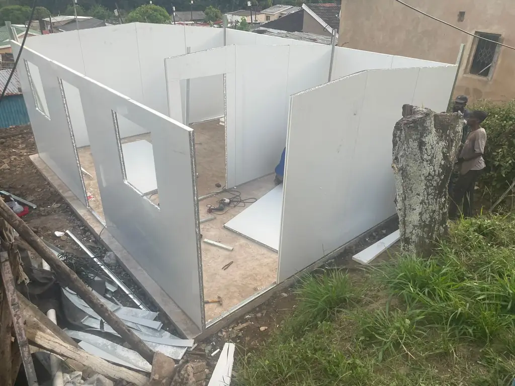 A UDRS unit's steel wall frame going up next to an existing home