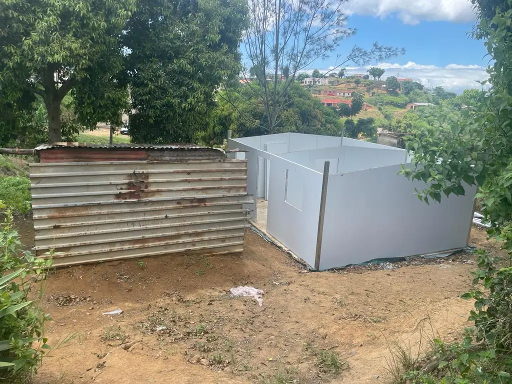 A UDRS modular unit built beside the corrugated-iron shack it replaces