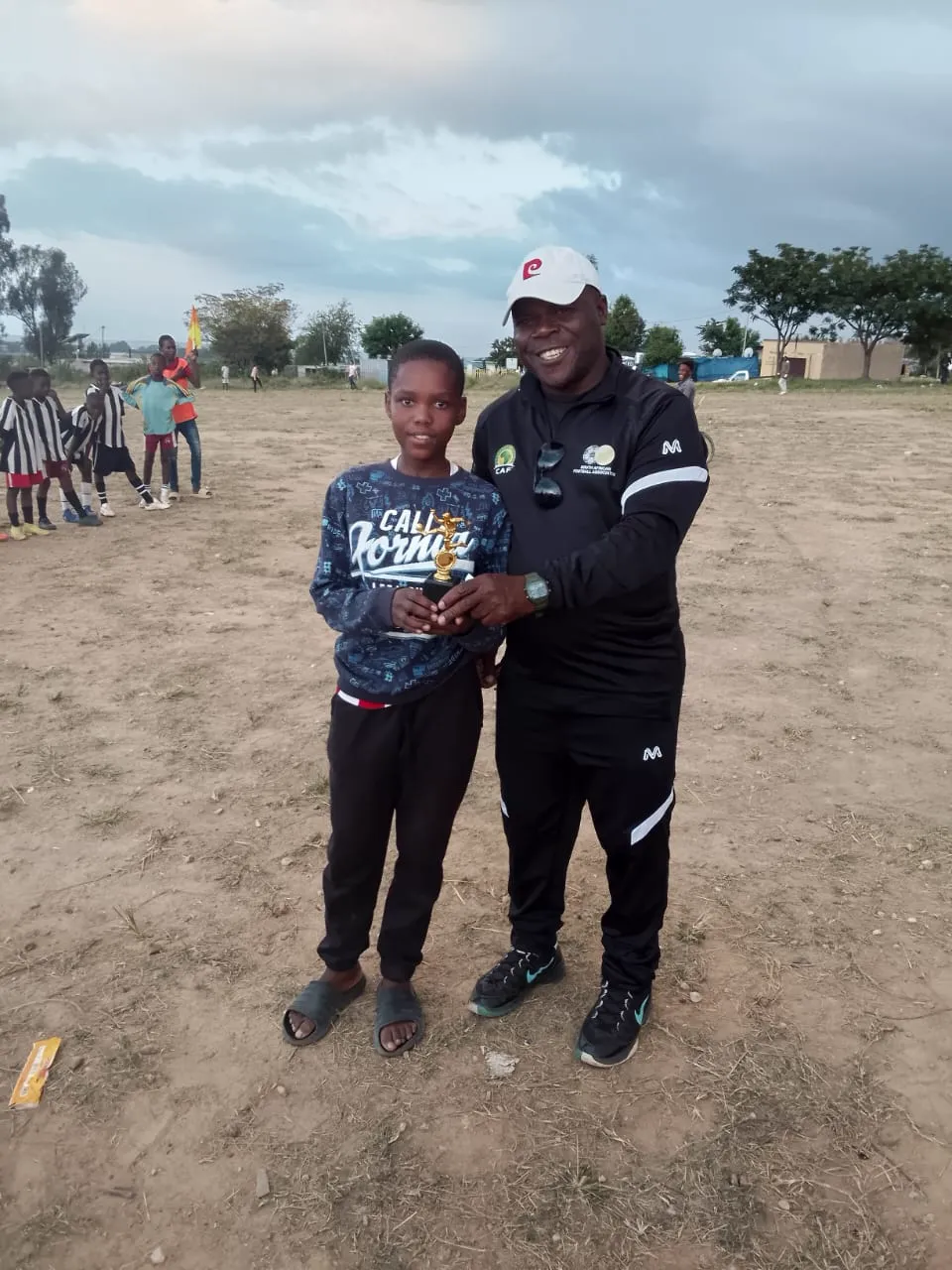 A player receiving a player-of-the-match trophy from a coach